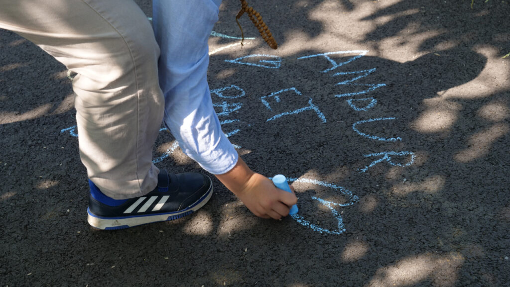 Un enfant trace à la craie "Amour et paix" sur le sol | Photo BORNYBUZZ / Aurélien ZANN