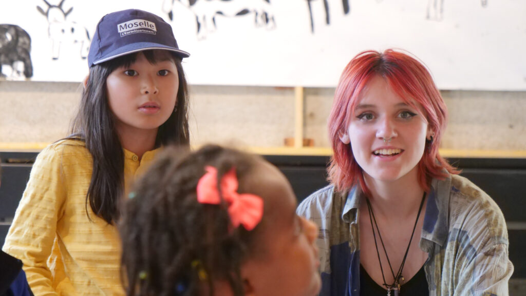 Une stagiaire de l’association Bouche à Oreille (BAO), avec les enfants du P'tit Lab. Accrochage de l'exposition Portraits sonores, le 6 juillet au Cloître des Récollets à Metz | Photo et graphisme BORNYBUZZ / Aurélien ZANN