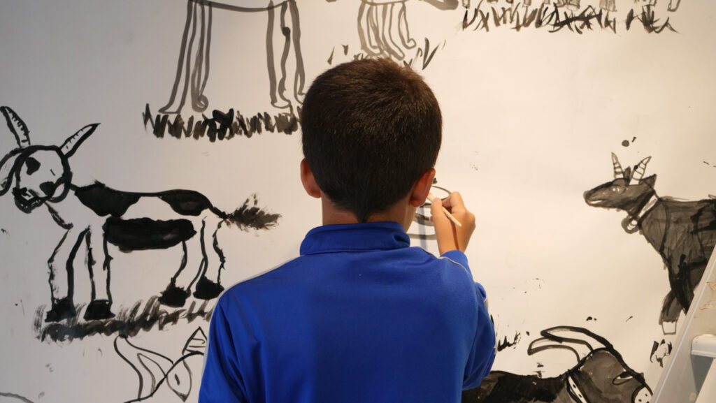 Un enfant du P'tit Lab dessine une fresque à l'encre de chine pour l'exposition Portraits sonores de l’association Bouche à Oreille (BAO). Le 6 juillet au Cloître des Récollets à Metz | Photo et graphisme BORNYBUZZ / Aurélien ZANN